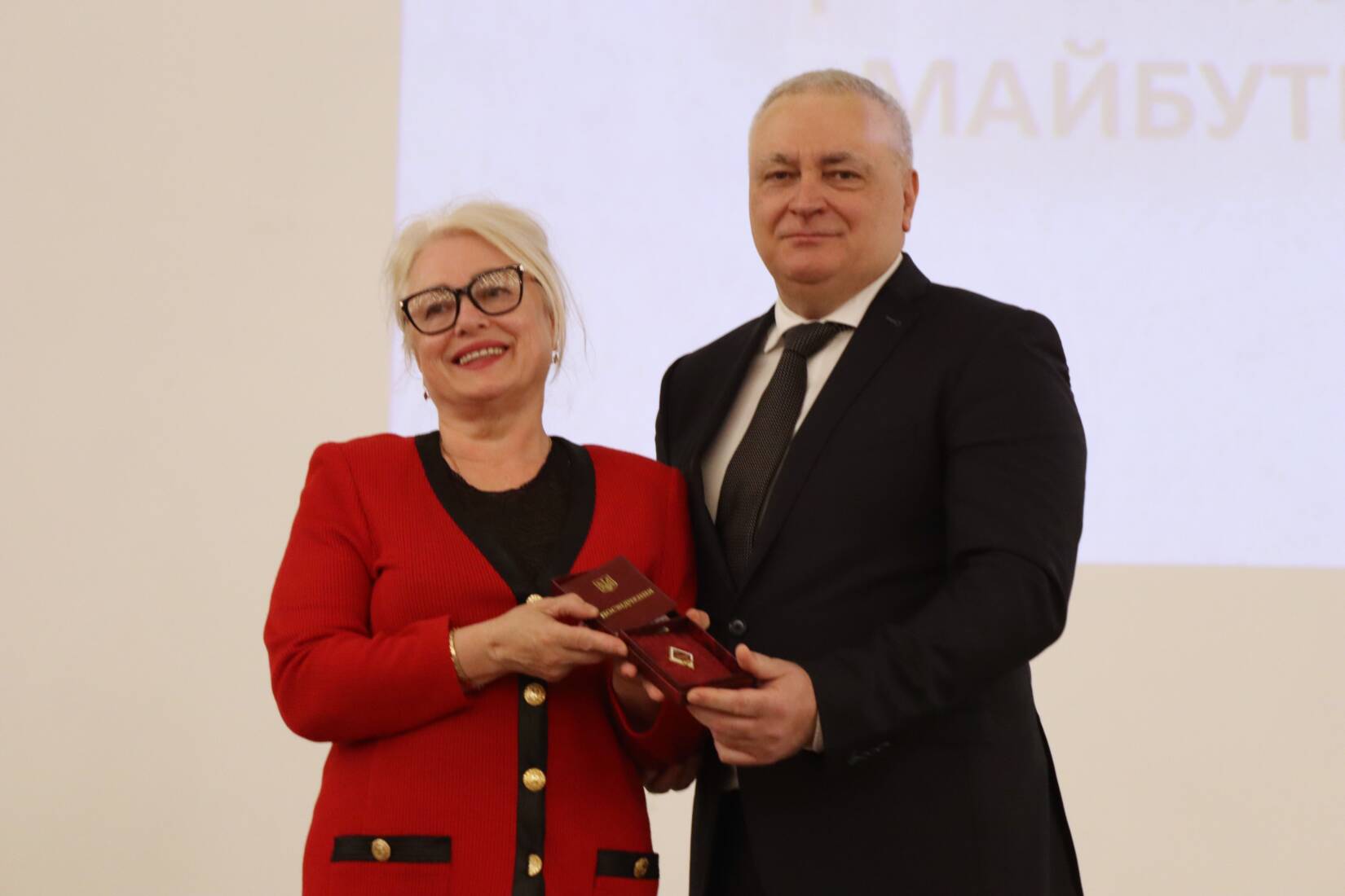 Володимир Смоланка вручає Марії Медведь нагрудний знак "Відмінник світи" до 80-річчя УжНУ
